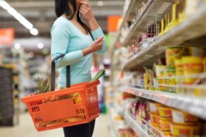 donna che fa la spesa al supermercato con il cestino attaccato al braccio