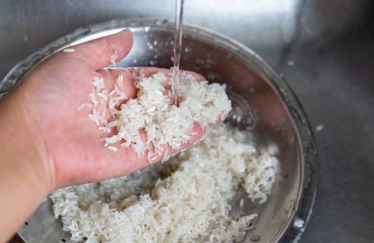 persona che lava il riso sotto l'acqua