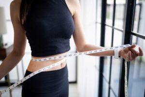 Una donna in perfetta forma che si misura il punto vita con un metro da sarta